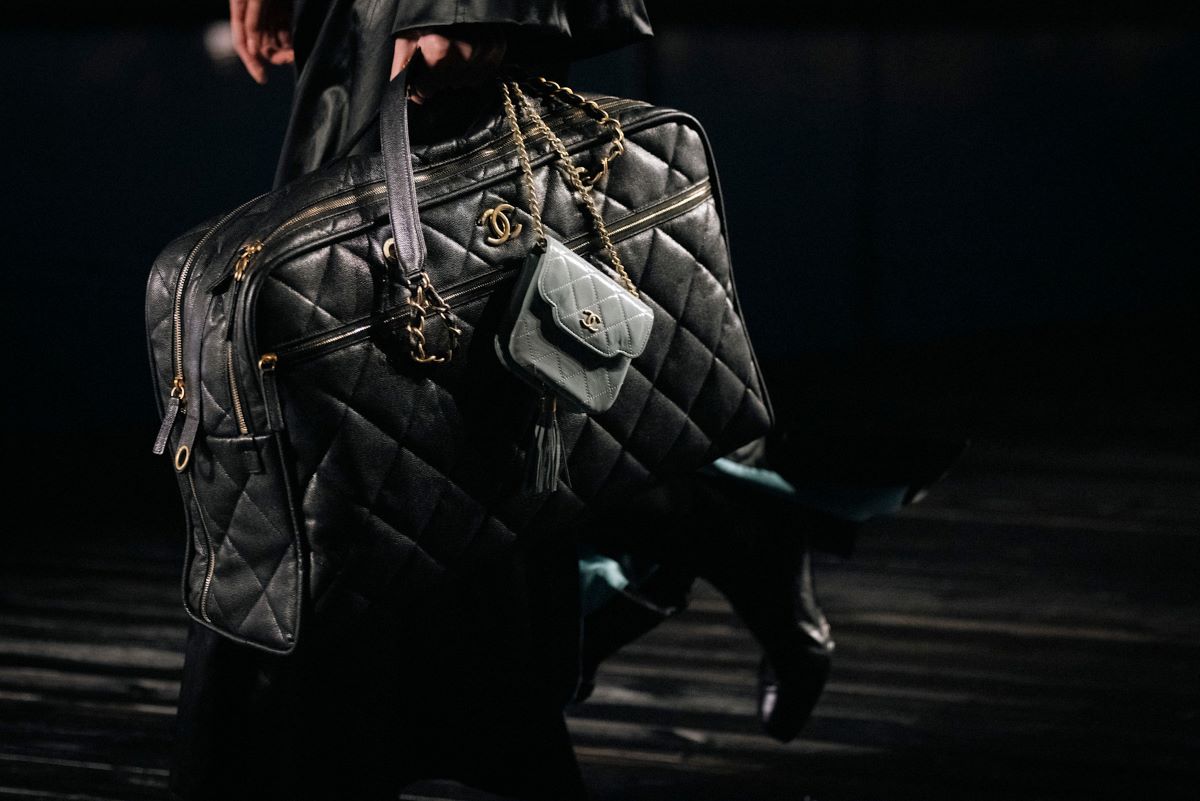 Firma badawczo-audytowa KPMG opublikowała 15. raport opisujący stan rynku dóbr luksusowych w Polsce. Zgodnie z jego treścią, przez ostatnie dwanaście miesięcy dwucyfrowo rosła liczba osób zarabiających nad Wisłą powyżej 1 mln zł brutto rocznie. Grubsze portfele przełożyły się na rozwój całej kategorii, dzięki czemu w porównaniu do zeszłorocznych danych polski rynek dóbr luksusowych urósł o 24,6 proc. Zbliżenie na dużą, czarną torbę podróżną Chanel. Artykuł stworzony z czarnej, pikowanej skóry dopełniony jest złotymi elementami takimi jak zamki, loga.