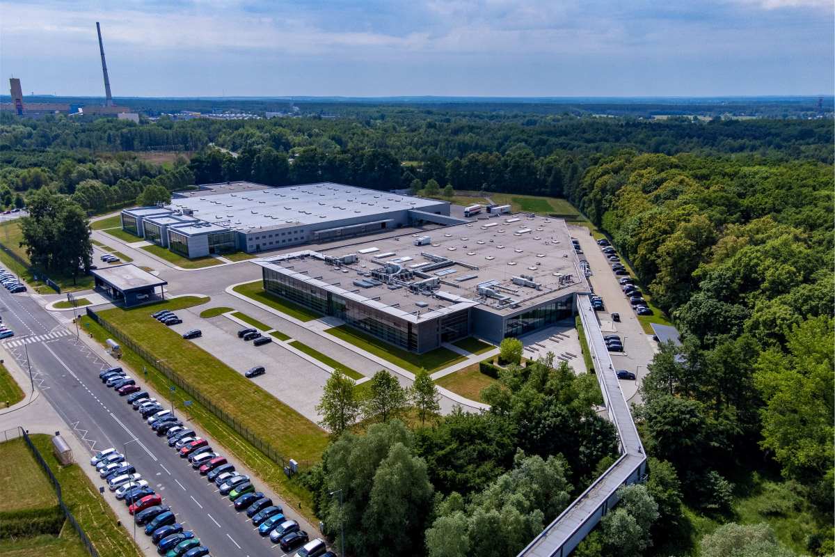 Spółka CCC zapowiedziała dużą inwestycję, która pozwoli wzmocnić jej pozycję na rynku i przyspieszyć rozwój marki HalfPrice. W Polkowicach powstanie nowoczesne centrum logistyczne, uzupełniające obecne zaplecze. Szacunkowa wartość całego projektu to około 200 mln zł. Jeszcze przed kilkunastoma miesiącami polski gigant borykał się z finansowymi turbulencjami, dzisiaj CCC inwestuje mocno myśląc o przyszłości i ustalaniu nowych standardów branżowych. Widok z lotu ptaka na kompleks budynków Grupy CCC w Polkowicach, otoczony zielenią i parkingami. Nowoczesna infrastruktura logistyczna stanowi część ambitnego planu inwestycyjnego – CCC inwestuje w rozwój sieci HalfPrice i wzmocnienie swojej pozycji w regionie.