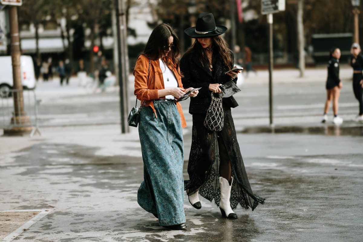 19 stycznia 2024 roku wejść w życie może blokada działalności TikToka w Stanach Zjednoczonych. Świat mody przyjmuje tę informację z niemałym poruszeniem. Platforma jest motorem napędowym viralowych trendów oraz jednym z głównych kanałów komunikacji z pokoleniem Z. Jak branża mody odnajdzie się w nowej rzeczywistości? Czy zakaz TikToka w USA stanie się szansą na rozwój innych kanałów? A może okaże się zagrożeniem dla marek opartych na sprzedaży w social mediach? Zdjęcie przedstawia dwie kobiety ubrane w stylowe, eklektyczne stroje, spacerujące ulicą. Jedna z nich trzyma telefon, co symbolicznie może nawiązywać do dyskusji o wpływie technologii na modę. W kontekście zakazu TikToka w USA obraz podkreśla znaczenie platformy dla promocji stylu i kreowania trendów.