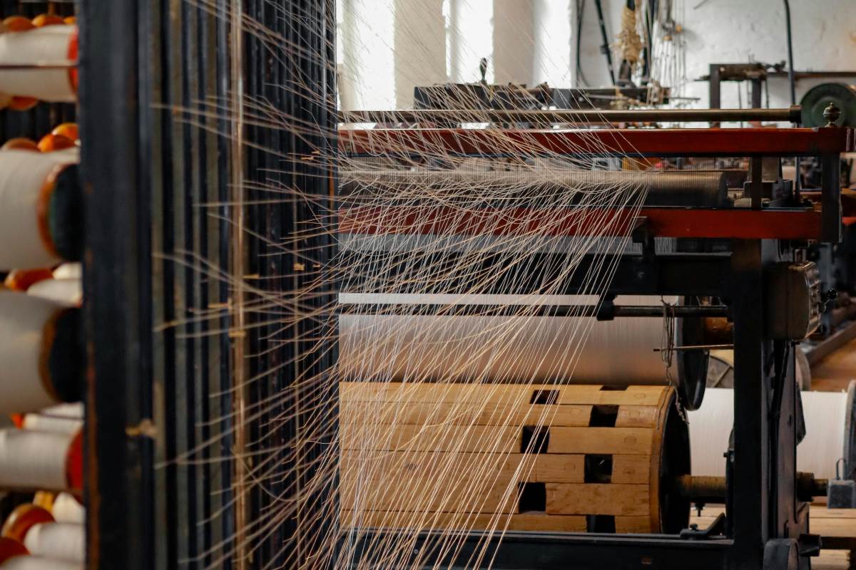 Po niemal dwóch stuleciach działalności jeden z najstarszych niemieckich producentów tekstyliów, Langheinrich, ogłasza koniec swojej historii. Firma, która przez 193 lata była symbolem jakości i rzemieślniczej tradycji, nie zdołała przetrwać w obliczu zmieniających się warunków rynkowych. Mimo podjęcia licznych prób ratowania przedsiębiorstwa, zarząd zdecydował o jego zamknięciu. Oznacza to bankructwo słynnego producenta tekstyliów. Co doprowadziło do upadku marki o tak bogatej tradycji? Na zdjęciu widzimy fragment maszyn tekstylnych w działającej fabryce, gdzie nici są rozwijane i prowadzone przez skomplikowany system mechanizmów. Obraz ten symbolizuje bankructwo słynnego producenta tekstyliów, podkreślając skomplikowaną historię przemysłową i wyzwania, z którymi zmagała się firma w zmieniającej się rzeczywistości rynkowej.