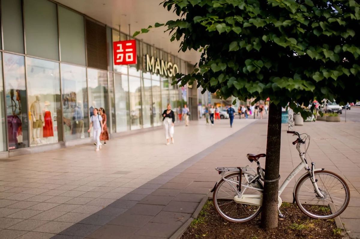 Zara, jeden z najbardziej rozpoznawalnych salonów hiszpańskiej sieci Inditex w centrum Warszawy, zniknęła z Domów Towarowych Wars Sawa Junior. Co ważne – nie pozostawi to jednak pustki w prestiżowej przestrzeni przy ul. Marszałkowskiej 104-122. Według nieoficjalnych informacji, wkroczy tam bowiem japoński gigant odzieżowy, Uniqlo, planujący dalszą ekspansję w Polsce. Zara na Marszałkowskiej zniknęła z Wars Sawa Junior w Warszawie. Na zdjęciu budynek handlowy z witrynami sklepów Uniqlo i Mango, widoczny po lewej stronie. Na pierwszym planie, pod drzewem, zaparkowany jest biały rower. Na chodniku poruszają się przechodnie, a w tle widać miejską ulicę z większym ruchem pieszym.