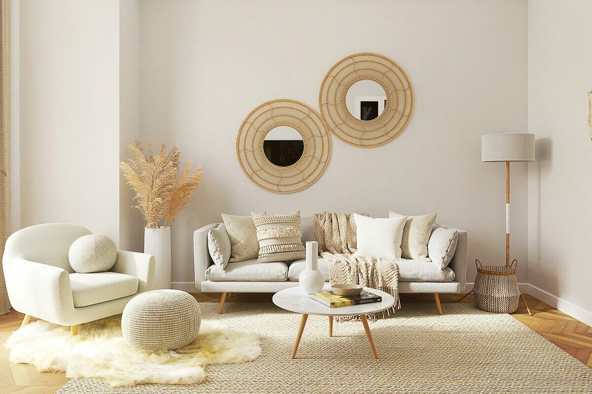Zdjęcie nowoczesnego wnętrza, odzwierciedlającego zamknięcie i likwidację Reserved Home. Wnętrza zdobią białe ściany, dwa lustra, biała sofa, fotel i dekoracyjne poduszki. Pośrodku stoi mały stolik kawowy z drewnianymi nogami i dywanem w stylu owczej skóry.