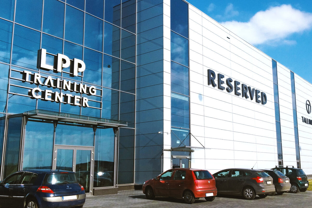 Kara dla LPP od KNF. Zdjęcie siedziby LPP – nowoczesnego, przeszklonego budynku z zaparkowanymi samochodami przed nim. Na budynku widnieje napis