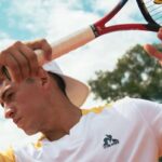 Le Coq Sportif: Ponad wiek w branży wyposażenia francuskich sportowców. Zdjęcie przedstawia tenisistę w markowej odzieży trzymającego sprzęt.