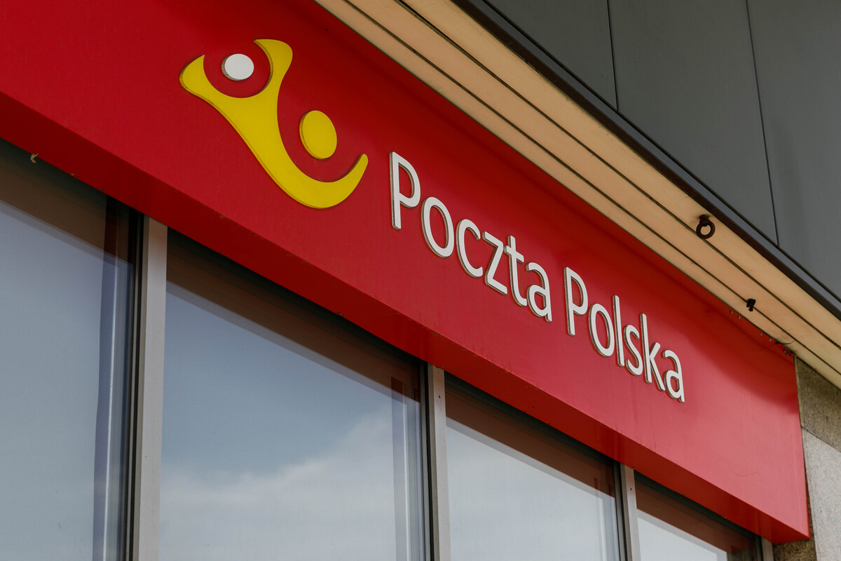 Poczta Stanów Zjednoczonych. Przesyłki zatrzymane. Zdjęcie szyldu Poczty Polskiej – czerwony z żółtym logo i białym napisem, wiszący nad oknami.