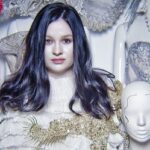 Kim jest Katarzyna Konieczka? Biografia i kariera. Portret bohaterki artykułu – projektantki kostiumów i projektantki Katarzyny Konieczki. Kobieta pozuje z rozpuszczonymi ciemnymi włosami i głową manekina.