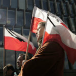 Żałoba narodowa w Polsce 26 kwietnia 2025 roku. Co to oznacza – czy sklepy będą otwarte? Na zdjęciu widać ludzi idących z polskimi flagami, oznaczonych czarnymi wstążkami na znak żałoby narodowej.