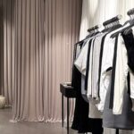 Salon Saint Body w Elektrowni Powiśle. Zbliżenie na stojak z body i koszulkami Saint Body w kontrastowych kolorach czerni i bieli; obok czarny stół i dwa lekkie ceramiczne wazony.