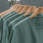 Ekologiczna odzież eksponowana na drewnianych stojakach. Zrównoważone tkaniny zastępują bawełnę, odzwierciedlając regulacje środowiskowe i ruchy ekologicznej mody.