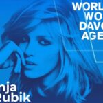 Niebieski plakat z Anją Rubik, z napisem „Anja Rubik” w lewym dolnym rogu. W prawym górnym rogu widnieje napis „World Woman Davos Agenda”. Anja ma długie, falujące włosy i opiera głowę na dłoni, wpatrując się w dal.