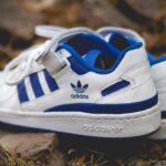 Wyciek danych Adidas – kogo dotyczy? Na zdjęciu widać białe buty sportowe Adidas z niebieskimi paskami, zapinane na rzep.