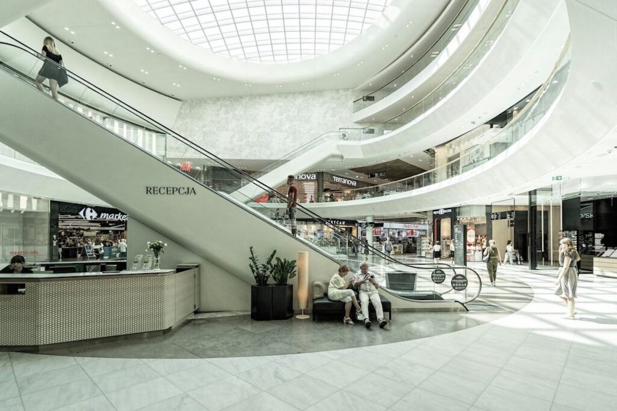 Dzisiaj przypada ostatnia chwila, aby dokonać większych zakupów przed nadchodzącym długim weekendem oraz dniem Wszystkich Świętych. Rosnące zainteresowanie konsumentów powoduje, że czołowe sieci – w tym Biedronka, Lidl, Aldi, Carrefour oraz Kaufland – przedłużają czas funkcjonowania swoich punktów 31 października 2025. Dowiedz się, jakie sklepy będą dostępne dłużej i gdzie zaopatrzysz się w niezbędne artykuły przed dniami z ograniczeniami w handlu. Piątek przed Wszystkimi Świętymi - co jest otwarte? Do której zrobimy zakupy? Na zdjęciu korytarz centrum handlowego i duże schody ruchome.