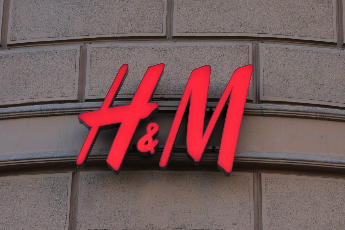 H&amp;M zamyka sklep przy Marszałkowskiej w Warszawie. Widok z bliska na czerwone, rozświetlone logo H&amp;M, zamieszczone na beżowej, kamiennej elewacji budynku. Znaki &quot;H&quot; i &quot;M&quot; oraz symbol &quot;&amp;&quot; odznaczają się charakterystycznym, kaligraficznym stylem.