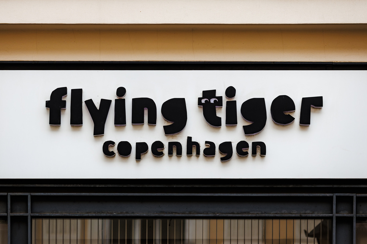 Szyld sklepu Flying Tiger Copenhagen. Czarny napis na białym tle.