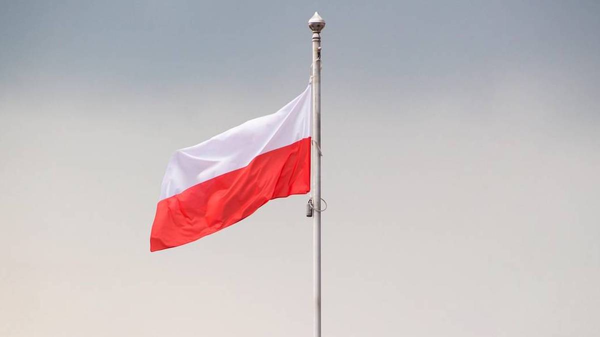 W związku ze zbliżającymi się obchodami Dnia Niepodległości, wielu obywateli Polski postanawia eksponować flagę państwową. Prezentacja symboli narodowych jest uregulowana odpowiednimi przepisami. Dobrze jest znać te reguły, ponieważ za sprofanowanie flagi można otrzymać karę pieniężną nawet do kwoty 5000 złotych. W bardziej dotkliwych sytuacjach, sankcją może być również pozbawienie wolności. Biało-czerwona flaga Polski powiewa na maszcie na tle jasnego nieba.
