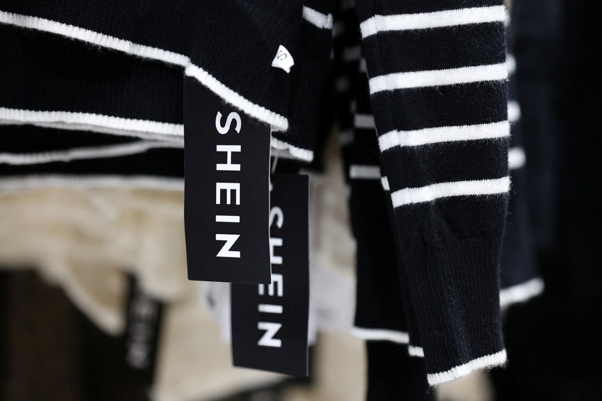W czwartek na lotnisku Roissy-CDG pod Paryżem zainicjowano szeroko zakrojoną inspekcję dostaw z Shein. Tysiące paczek znalazły się pod obserwacją urzędników celnych, a rząd Francji – z ministrami na miejscu zdarzenia – dał wyraźny komunikat: era bezkarnego handlu internetowego z Azji dobiega kresu. Akcja rozpoczęła się dzień po tym, jak władze uruchomiły postępowanie mające na celu wstrzymanie działalności platformy na terenie Francji. Kontrola paczek z Shein we Francji, 200 tysięcy przesyłek skontrolowanych na lotnisku. Na zdjęciu: metka z logo SHEIN na czarno-białym swetrze w paski, wiszącym na wieszaku.