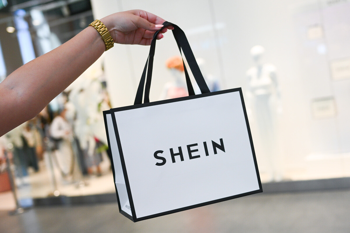 Francuskie organy ścigania odnalazły na Shein lalki o charakterze seksualnym podobne do dzieci. Dłoń dzierżąca białą torbę na zakupy z czarnym wykończeniem i czarnymi rączkami. Na torbie widnieje dużymi, czarnymi znakami wyraz &quot;SHEIN&quot;.