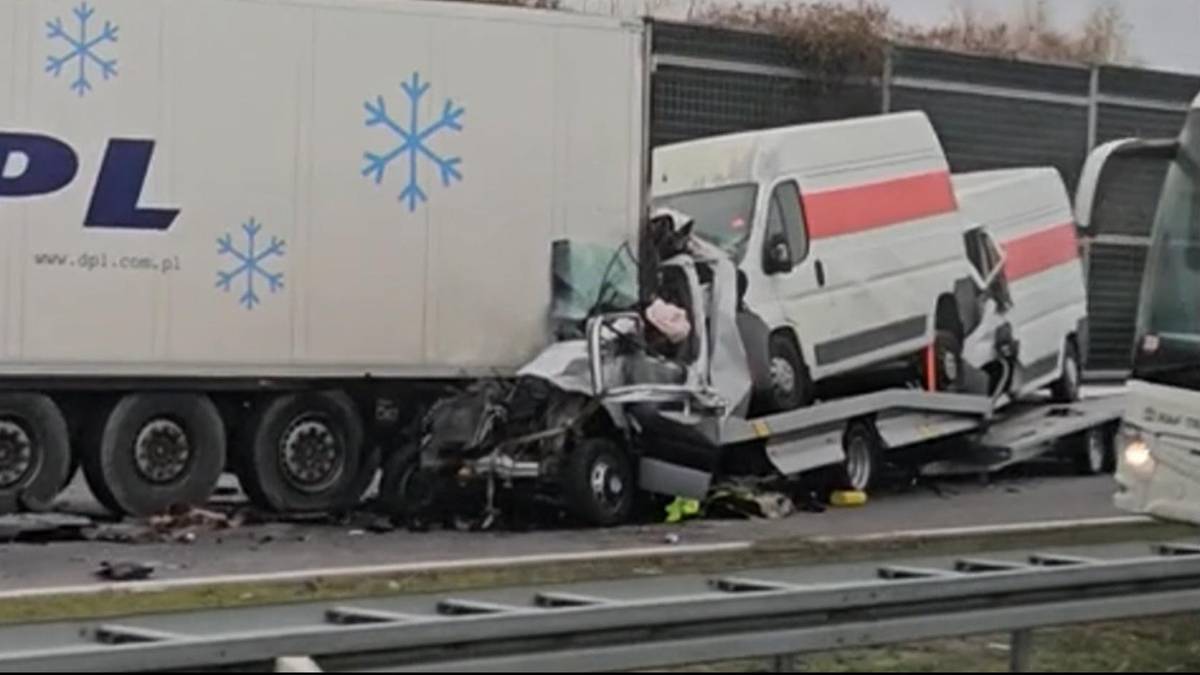 Zmiażdżona szoferka lawety z dwoma busami na pokładzie po zderzeniu z tyłem białej ciężar&oacute;wki na autostradzie.