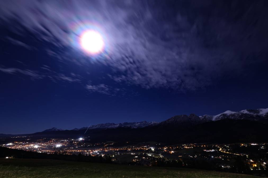 Tej nocy warto skierować spojrzenie w górę - czeka na nas widowiskowy spektakl. Nadchodzi superpełnia, znana również jako superksiężyc - chwila, kiedy nasz naturalny satelita zbliży się do Ziemi na najmniejszą odległość w tym roku. Z tego powodu Księżyc będzie emanował niezwykłym promieniowaniem i będzie wydawał się pokaźniejszy niż zazwyczaj, co już dokumentują pierwsze fotografie z różnych regionów Polski. Superpełnia Księżyca widoczna nad nocnym miastem