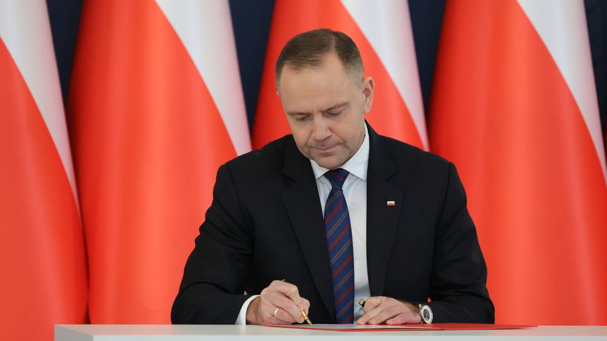 Gdyby ponowne głosowanie w wyborach prezydenckich, z udziałem tych samych konkurentów, miało miejsce teraz - ponownie triumfowałby Karol Nawrocki - to rezultat sondażu Opinia24 dla tygodnika "Polityka". Po upływie pierwszych stu dni sprawowania urzędu prezydenta, ponad 53 proc. uczestniczących w badaniu ocenia go jako "dobrego" i "bardzo dobrego". Karol Nawrocki, prezydent Polski, siedzi przy biurku i podpisuje dokument, w tle biało-czerwone flagi Polski.