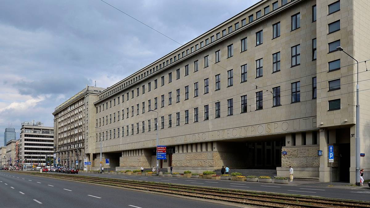 Budynek Sądu Okręgowego w Warszawie z betonową fasadą, widziany od strony ulicy z torami tramwajowymi.