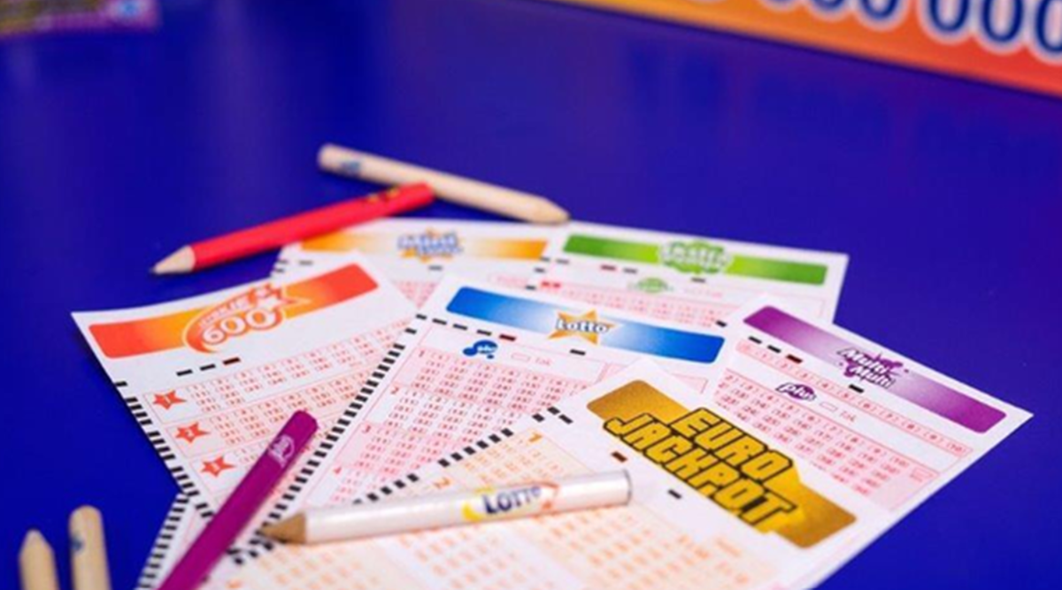 Zbliżenie na kilka kuponów gier liczbowych Lotto i Eurojackpot, obok leżą kredki i ołówki.
