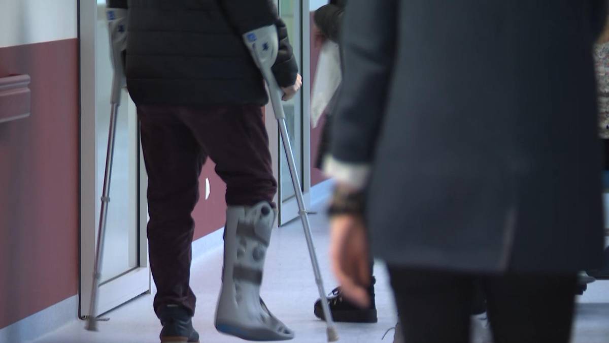 Osoba z nogą w gipsie poruszająca się o kulach w szpitalu.