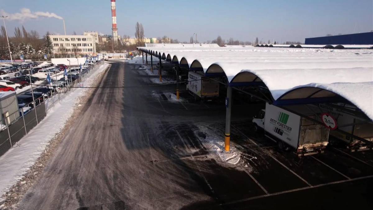 Zadaszony parking pokryty śniegiem z zaparkowanymi samochodami.