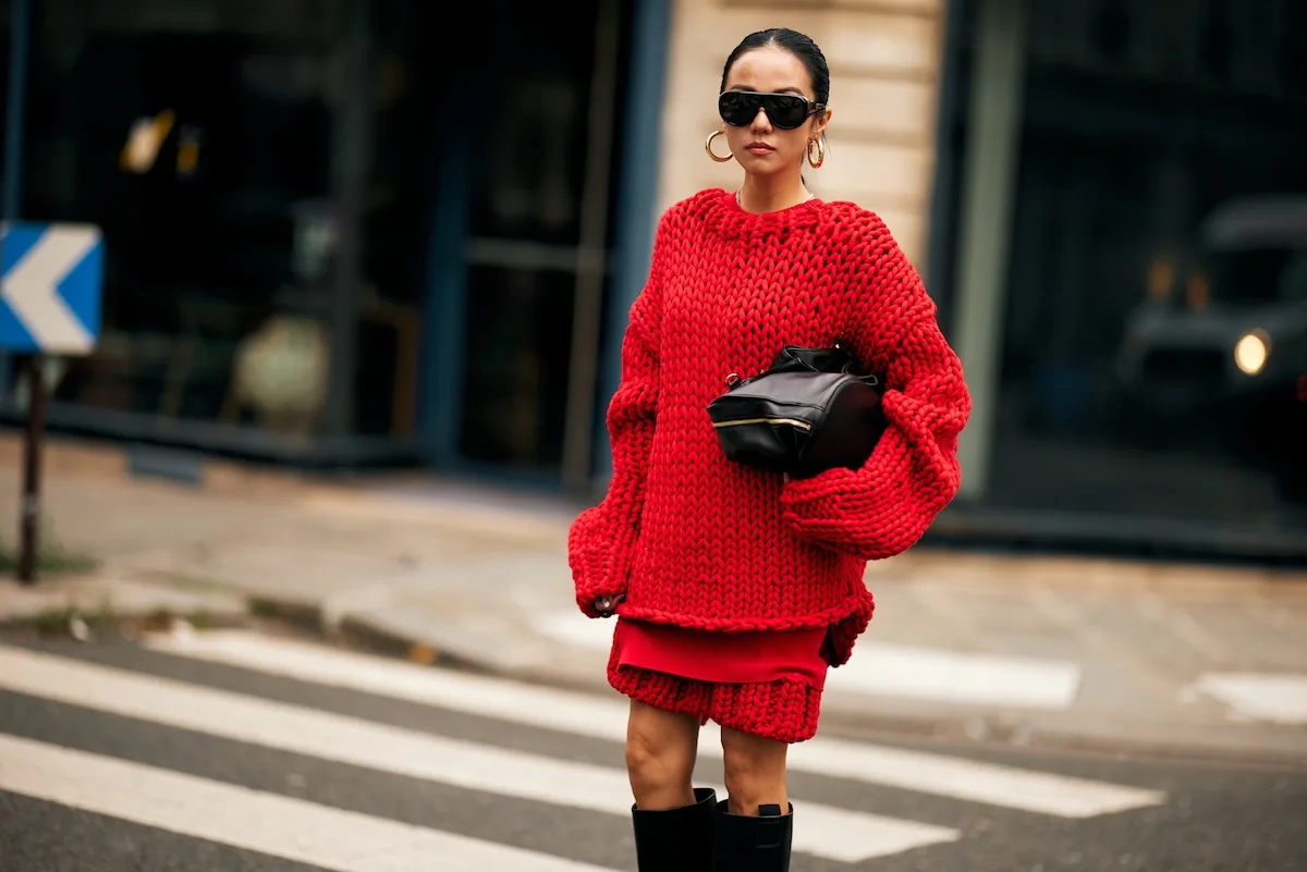 Wirtualne przymierzalnie mody. Na zdjęciu modelka w czerwonym Total looku, w ciemnych okularach i torebką pod pachą.