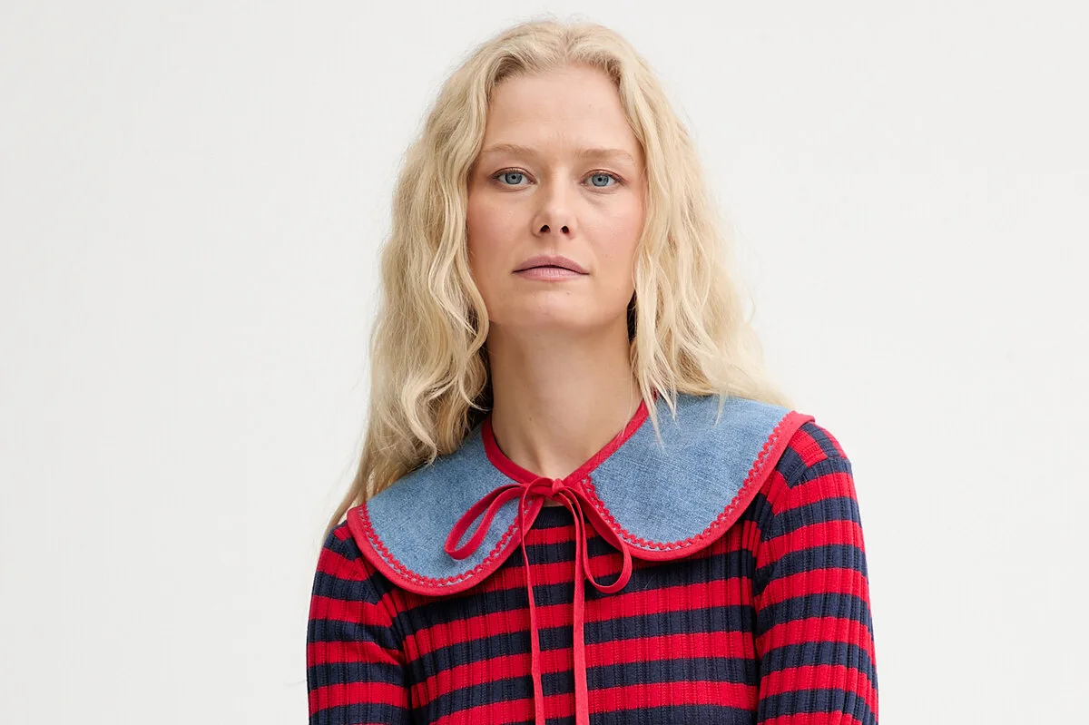 Wyniki finansowe Answear.com 2025. Portret kobiety o jasnych, falowanych włosach, ubranej w czerwono-granatową pasiastą bluzkę z dużym, dżinsowym kołnierzem, na jasnym tle.