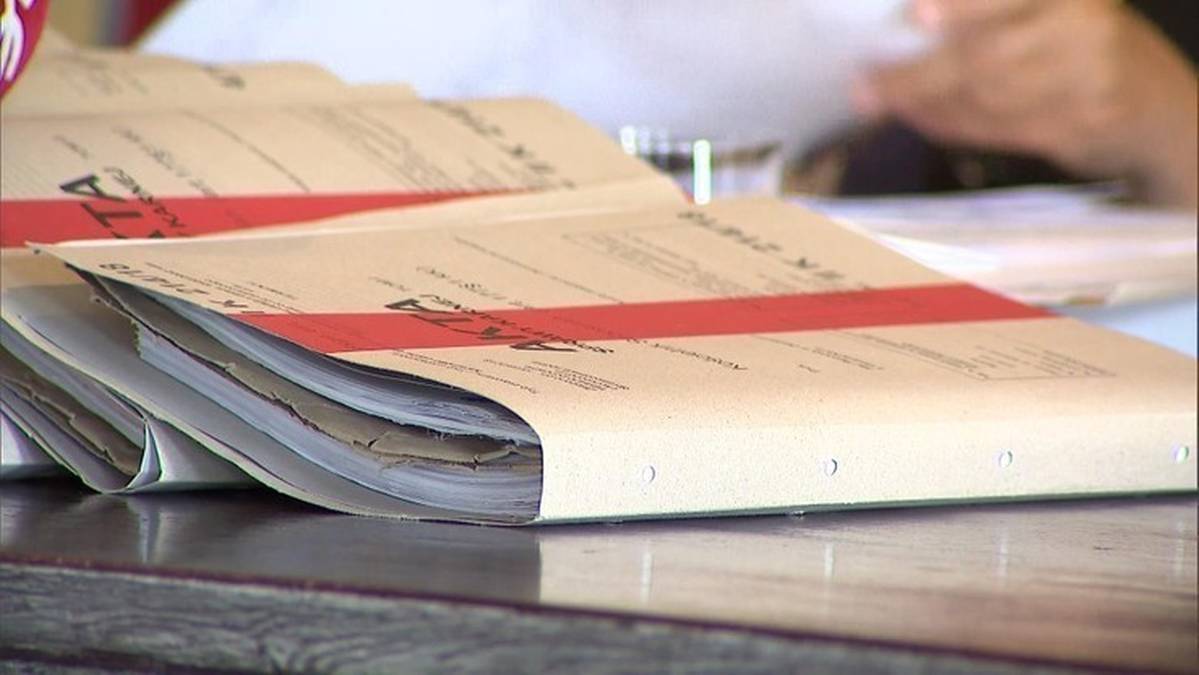 Stos papierowych dokumentów w teczkach, z czerwonym paskiem.