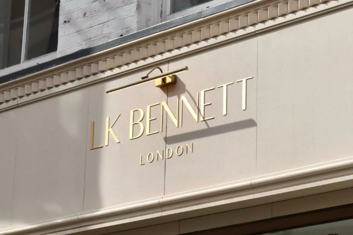 Złoty logotyp butiku L.K. Bennett na jasnej elewacji budynku w Londynie. Ulubiona marka księżnej Kate na skraju bankructwa, znana z szykownych kreacji odzieżowych i obuwniczych w stylu british chic.