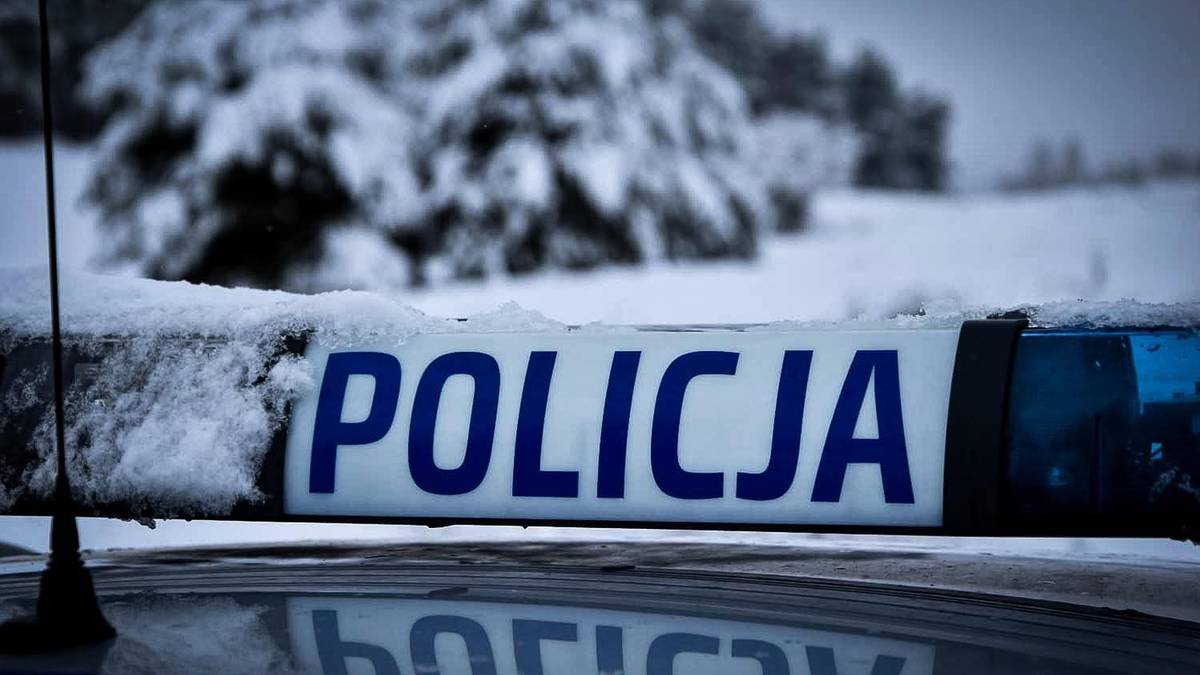 Napis POLICJA na taśmie policyjnej pokrytej śniegiem.
