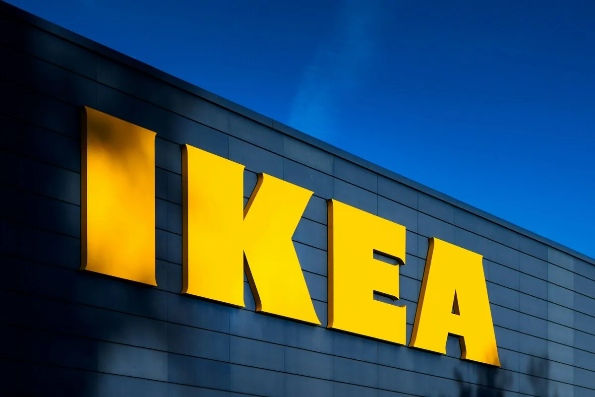 IKEA i Decathlon pod jednym dachem. Pierwszy taki sklep w historii. Żółty, podświetlony napis „IKEA” umieszczony na ciemnej elewacji budynku na tle głębokiego, niebieskiego nieba o zmierzchu.