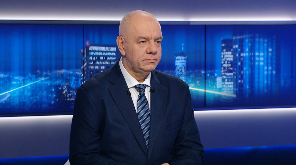 Mężczyzna w garniturze i krawacie siedzi podczas wywiadu.