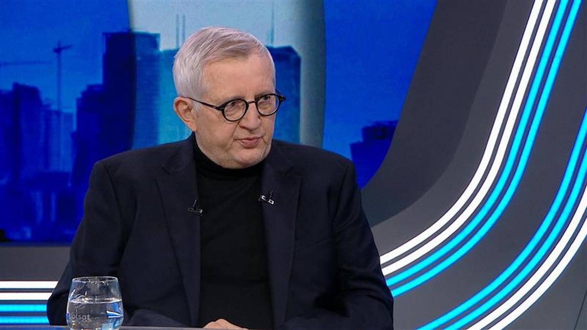 Mężczyzna w okularach siedzi w studiu telewizyjnym.