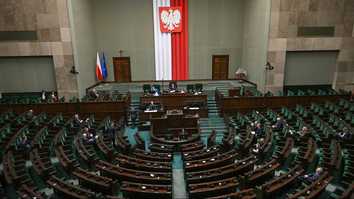 Wnętrze sali sejmowej z rzędami ław poselskich.