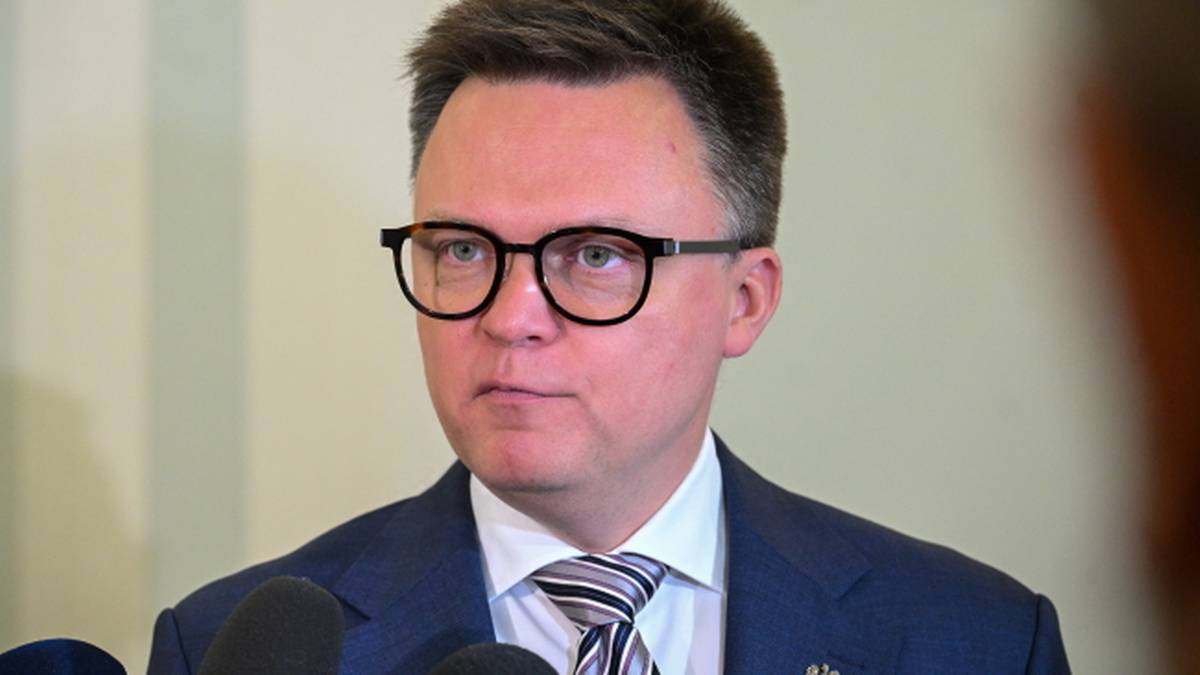 Portret mężczyzny w okularach i granatowym garniturze.