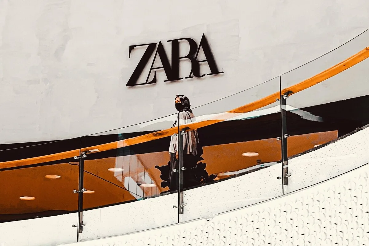 Wyniki finansowe Inditex 2025 rok. Postać stojąca na piętrze galerii handlowej przy szklanej balustradzie, na tle dużego logo sklepu Zara umieszczonego na ścianie.