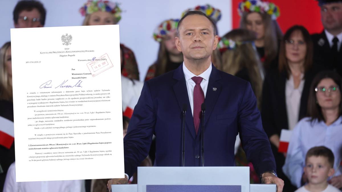 Zbigniew Bogucki stoi za m&oacute;wnicą z dokumentem w ręku, w tle grupa os&oacute;b