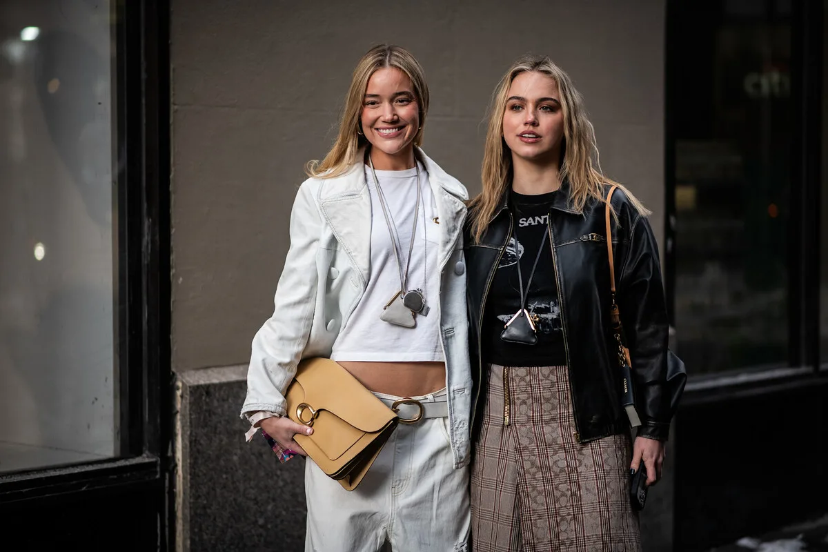 UE sankcje dla platform handlu elektronicznego. Dwie kobiety w szykownych kreacjach miejskich z luksusowymi torebkami, sfotografowane na ulicy miasta. Fotografia obrazuje zagadnienie e-handlu i przywozu niedrogich wyrobów do UE, które mogą być objęte nowymi regulacjami i dodatkowymi obciążeniami.