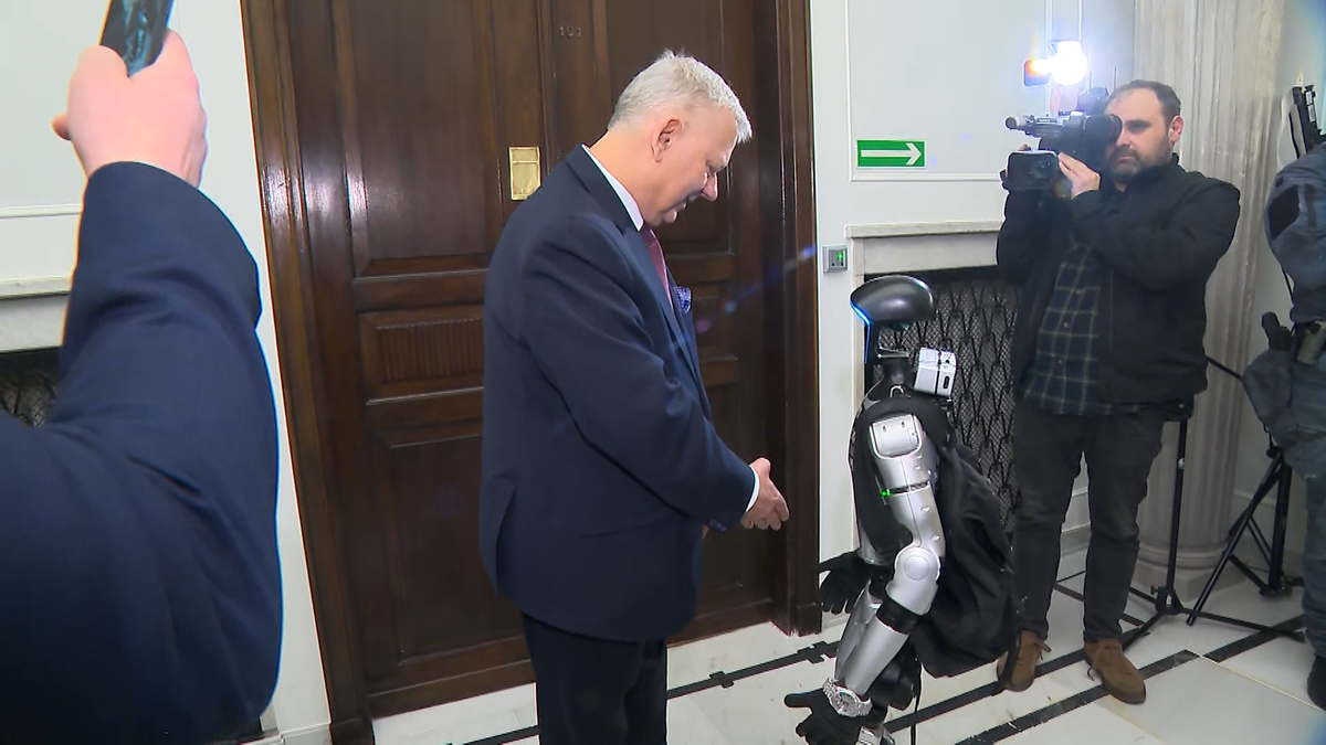 Humanoidalny robot Edward Warchocki stoi obok posła Marka Suskiego w korytarzu sejmowym.