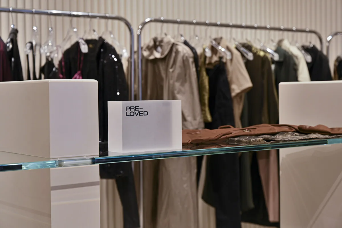 Ekspozycja odzieży z etykietą „pre-loved” w sklepie H&amp;M, akcentująca rozwój segmentu wtórnej sprzedaży. Stanowi to przykład działań firmy, które mają na celu przedłużenie żywotności produktów i ograniczenie nadprodukcji.