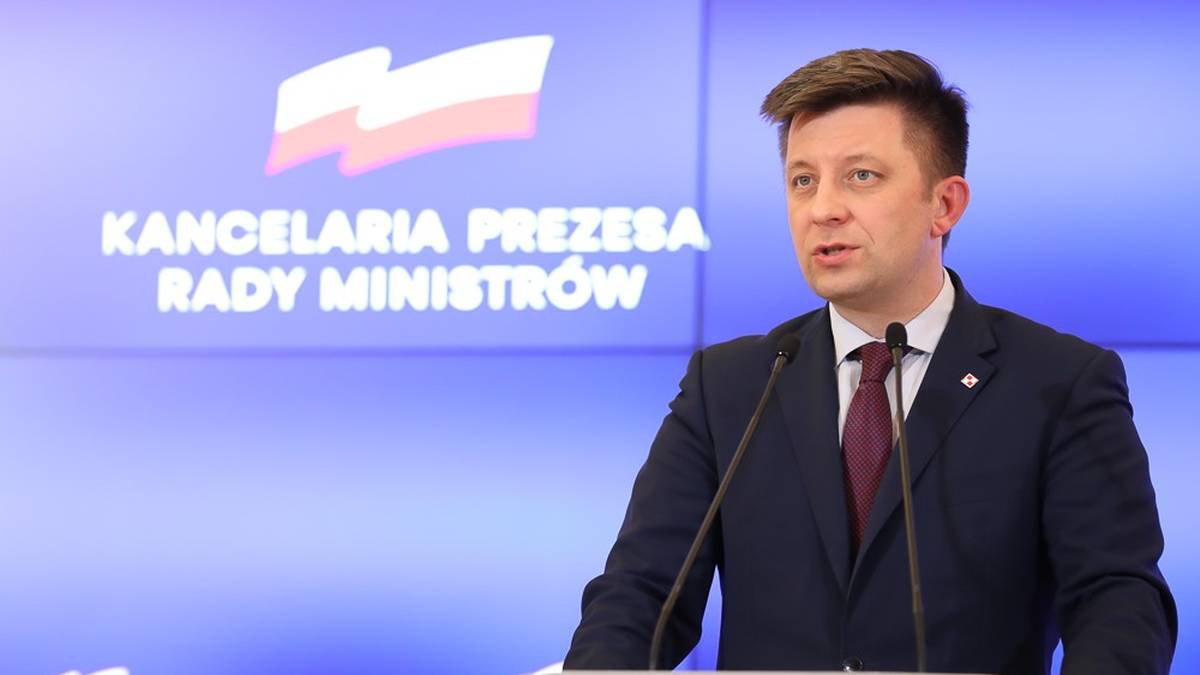 Michał Dworczyk przemawia przy m&oacute;wnicy na tle logo Kancelarii Prezesa Rady Ministr&oacute;w.