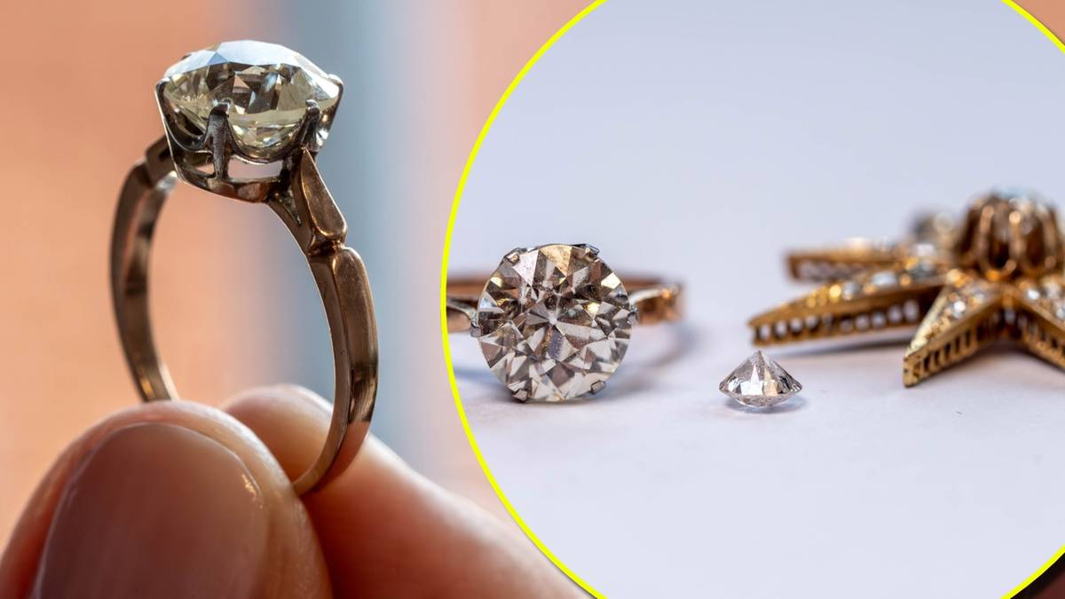 Zbliżenie na złoty pierścionek z dużym brylantem oraz kilka mniejszych diament&oacute;w.