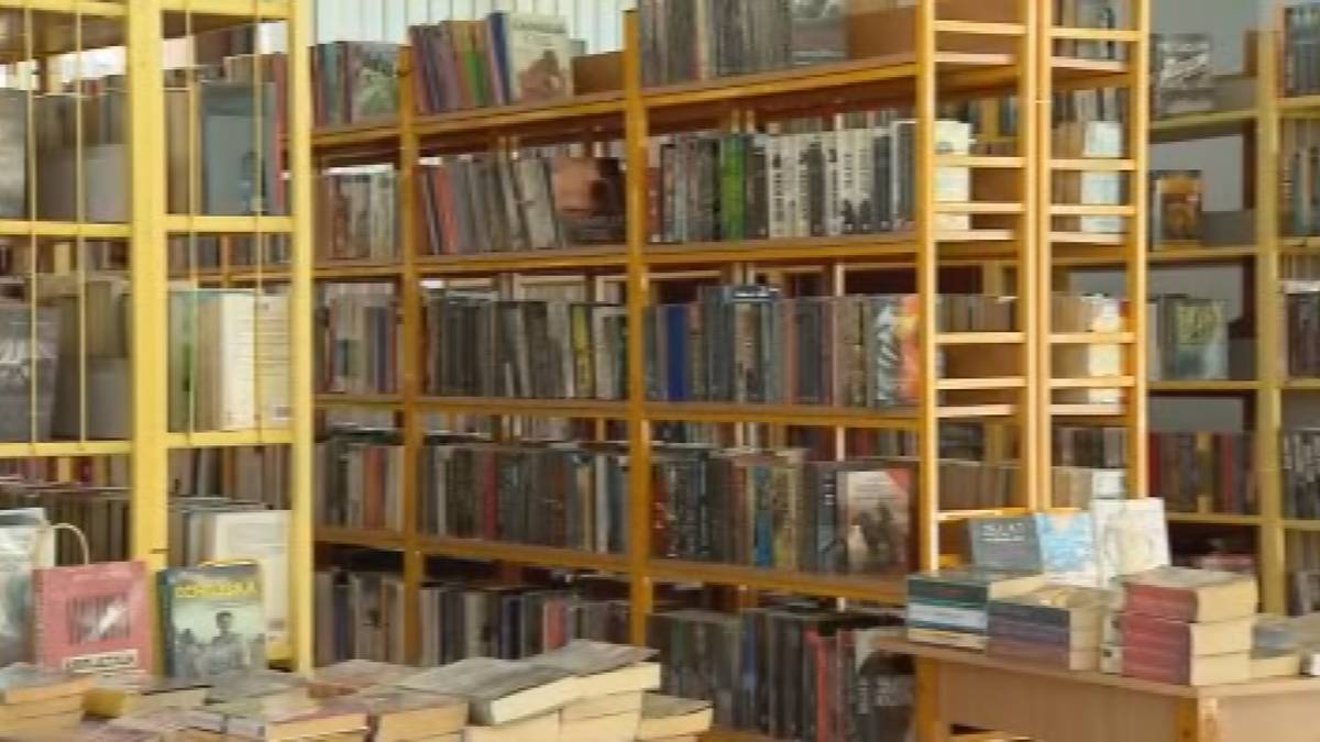 Rzędy regał&oacute;w wypełnionych książkami w bibliotece lub księgarni.