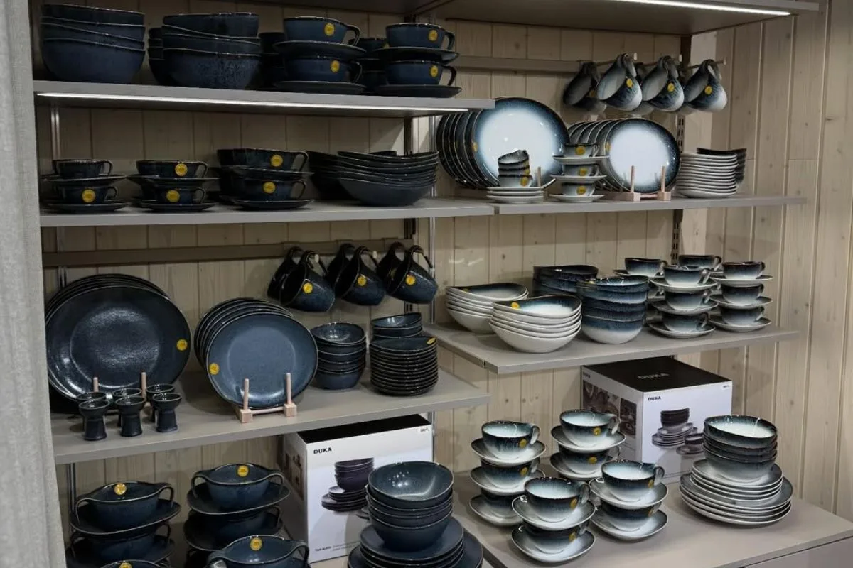 Kryzys Duka w Polsce. Prezentacja naczyń kuchennych na regałach w sklepie, włączająca talerze, bulionówki i kubki w nowoczesnym stylu. Takie kompozycje przez lata stanowiły normę w salonach Duka – obecnie ich ilość się zmniejsza wraz z ograniczaniem aktywności sieci.