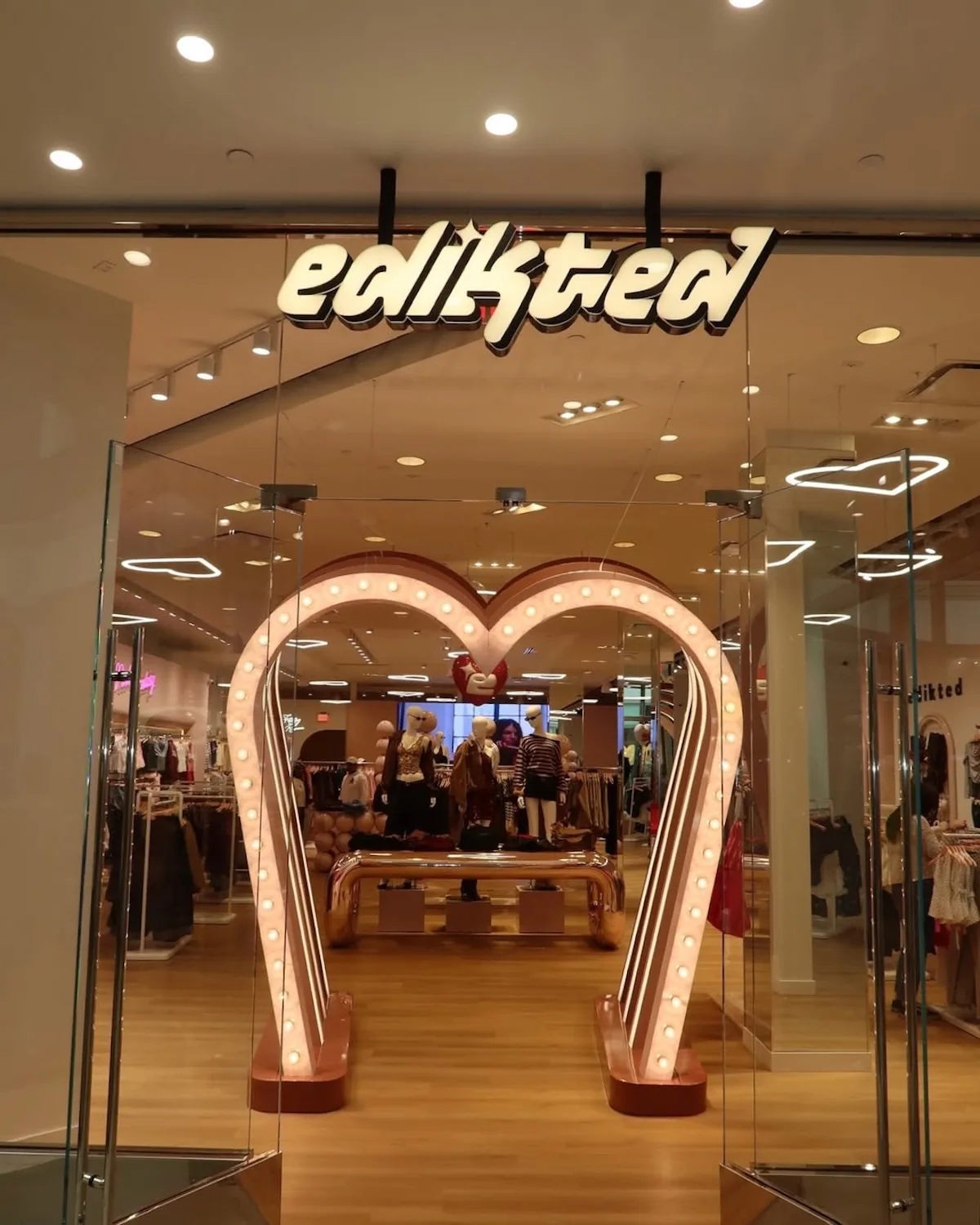 Wejście do sklepu Edikted z charakterystycznym logo i instalacją świetlną w formie serca, przyciągającą wzrok klientów. To przykład nowego etapu rozwoju marki, która tworzy sieć sklepów stacjonarnych w Europie.