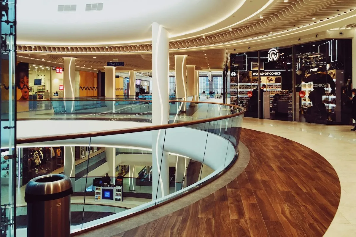 Wnętrze nowoczesnej galerii handlowej z zamkniętymi lub pustymi sklepami, symbolizujące ograniczone godziny handlu w Wielką Sobotę.