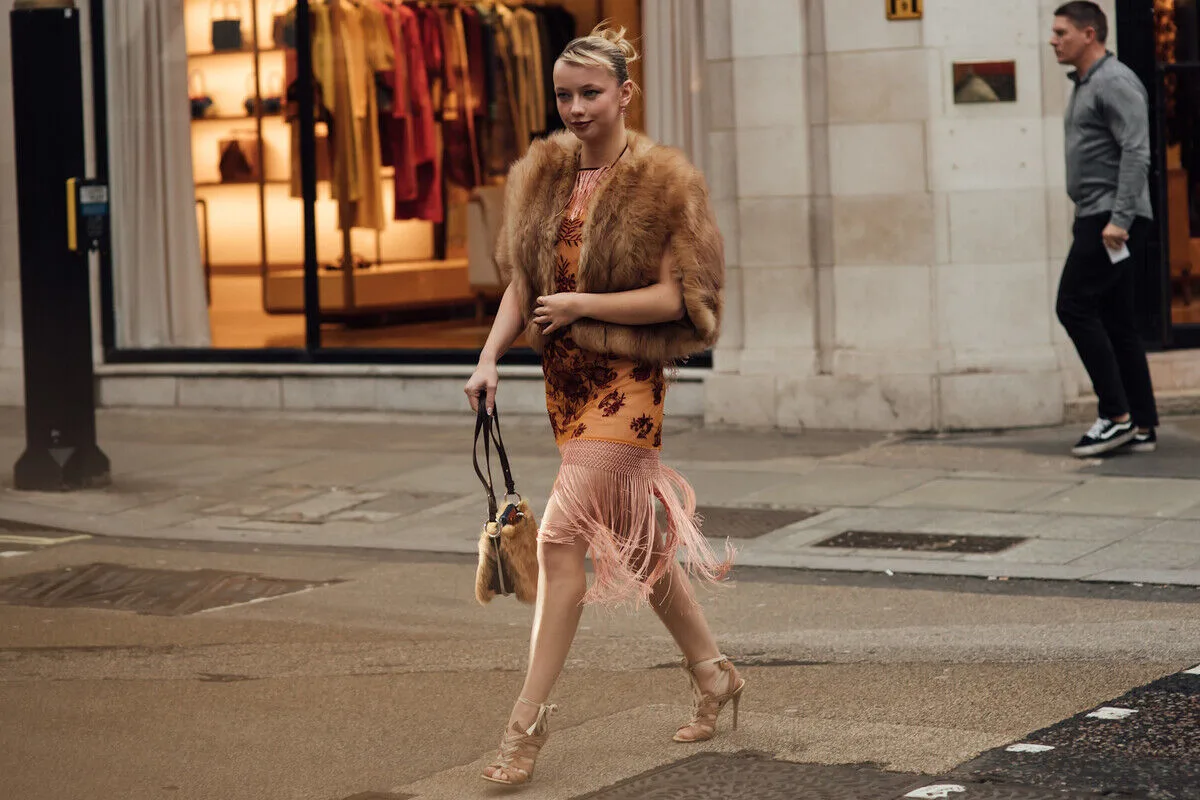 Elegancko odziana kobieta na ulicy w szykownej stylizacji, odzwierciedlającej trendy w modzie i rozsądną konsumpcję. Fotografia dobrze ilustruje kontekst rynku wtórnego i powiększającego się wpływu platform takich jak Vinted, co koresponduje z tematem wyniki finansowe Vinted 2025 oraz zmieniających się przyzwyczajeń zakupowych.